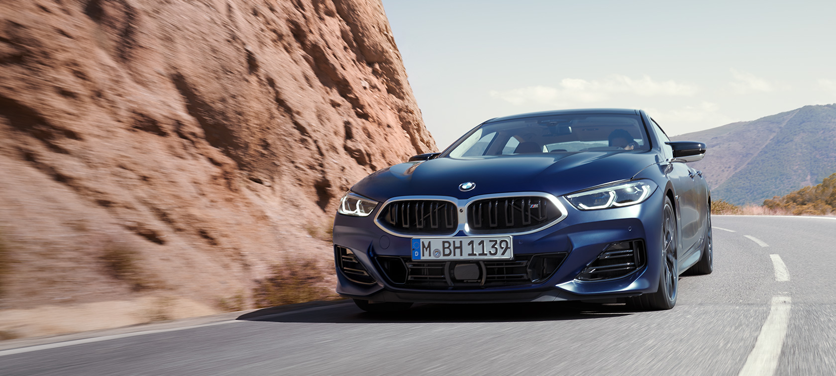 BMW 8 серії Gran Coupe G16 LCI Facelift 2022 BMW Individual у кольорі Frozen Tanzanite Blue metallic, вид спереду на три чверті під час руху на гірській дорозі