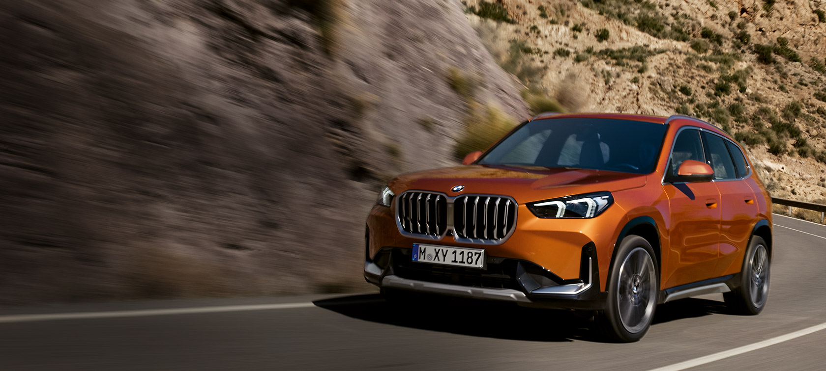 BMW X1 U11 xLine у кольорі Utah Orange metallic, вид спереду з поворотом у три чверті на грунтовій дорозі